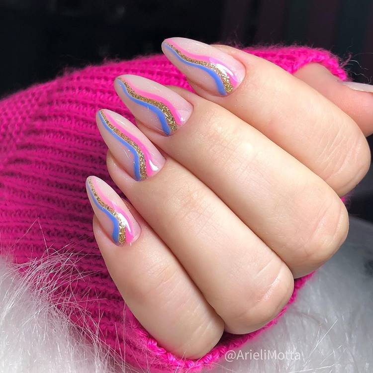 Mão com unhas decoradas coloridas: Polegar: nude com arcoíris azul, dourado e rosa em formato de onda Indicador: nude com arcoíris azul, dourado e rosa em formato de onda Médio: nude com arcoíris azul, dourado e rosa em formato de onda Anelar: nude com arcoíris azul, dourado e rosa em formato de onda Mínimo nude com arcoíris azul, dourado e rosa em formato de onda