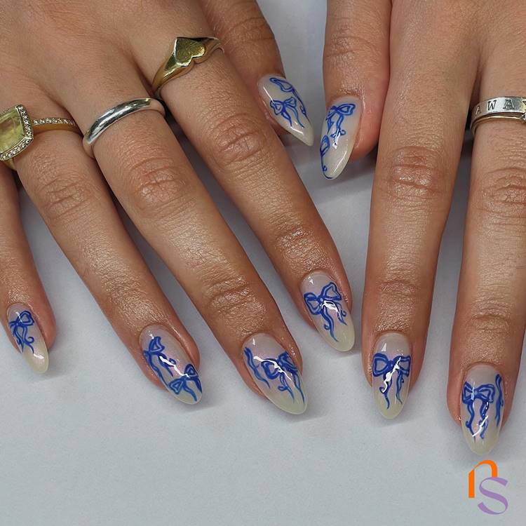 Unhas brancas decoradas com laços azuis