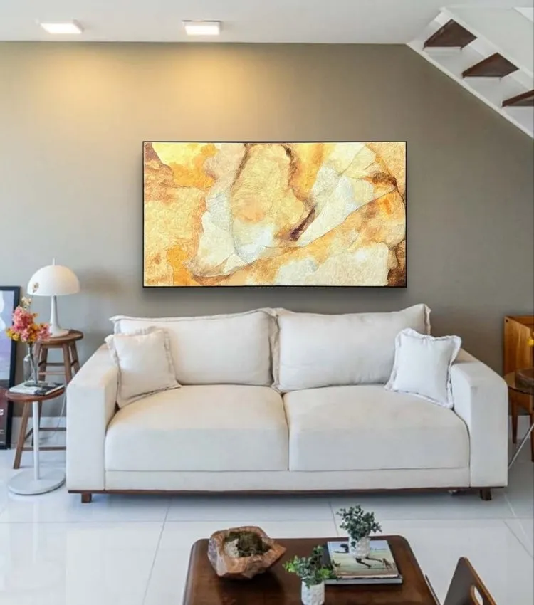 Sala decorada com quadro do artista plástico Adielson Rodrigues em tons de amarelo, cor tendência da decoração para 2026