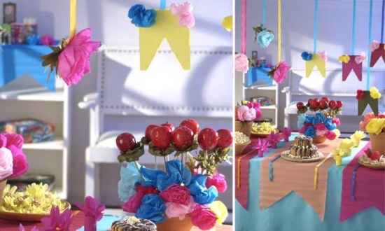 A imagem representa decorações de festa junina: mesa decorada com maça do amor, flores e bandeirinhas