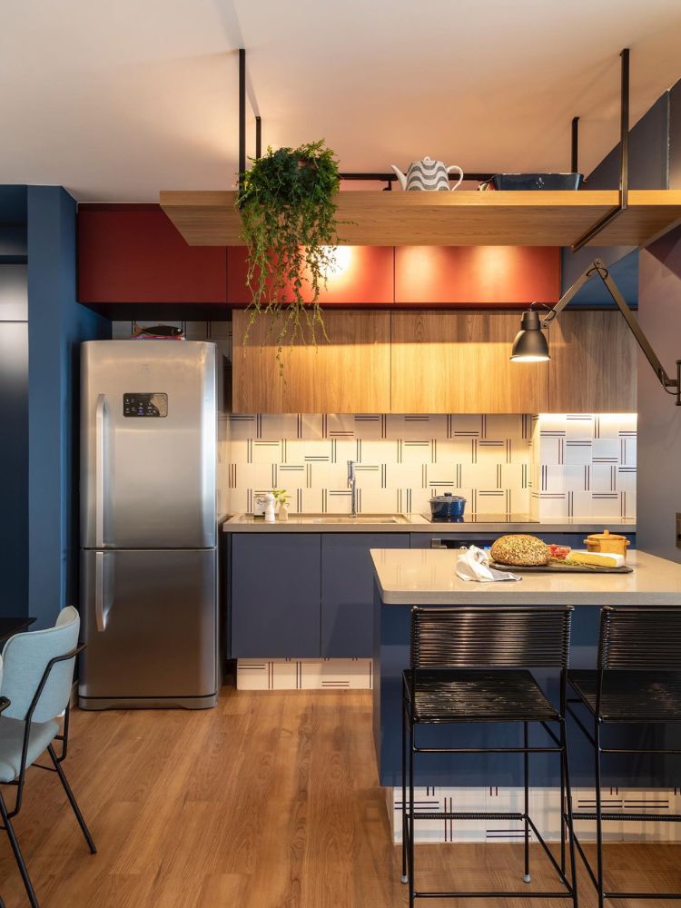 Cozinha colorida com paredes e armários azuis, azulejos geométricos, armários laranjas e decorações modernas 