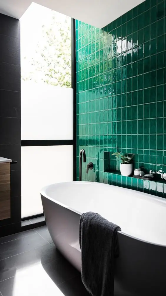 Banheiro com banheira branca, azulejos verdes e vaso no nicho