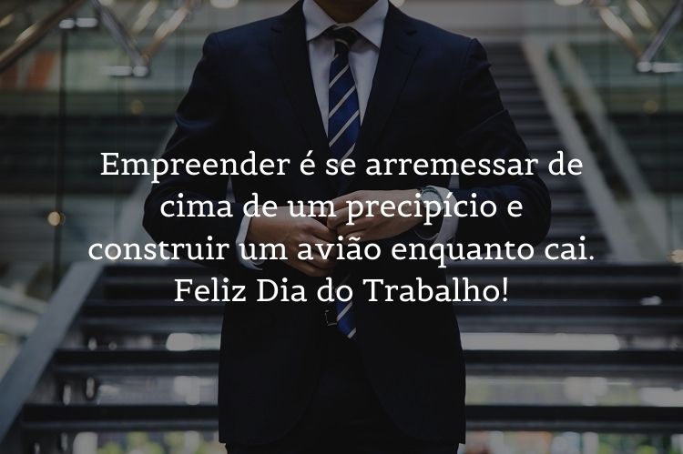 Foto de homem em escada arrumando o terno e frase "Empreender é se arremessar de cima de um precipício e construir um avião enquanto cai. Feliz Dia do Trabalho!"