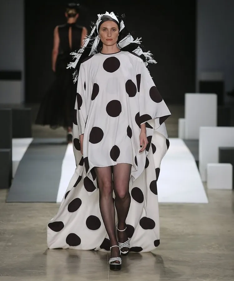 Foto de modelo na passarela usando vestido longo branco com bolinhas pretas