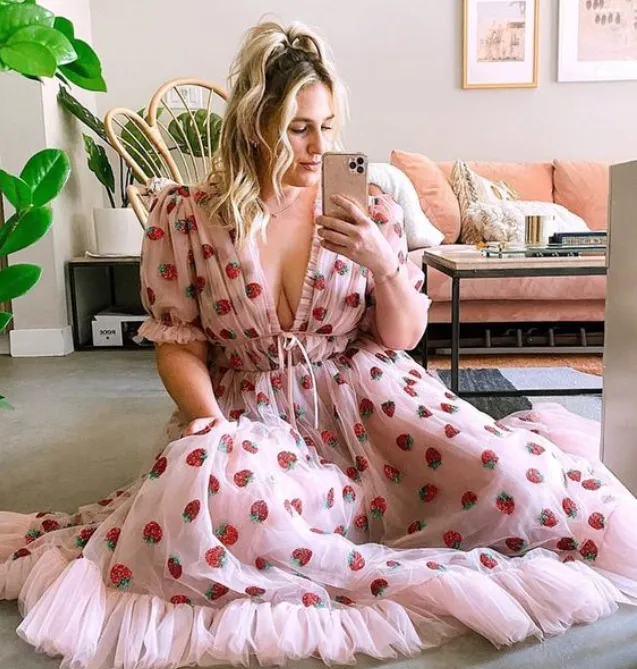 Mulher de pele clara com vestido de tule rosa com morangos