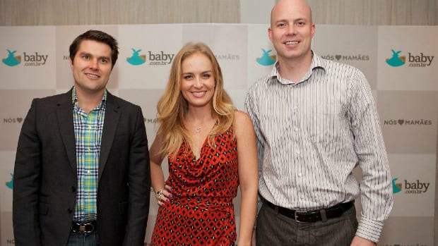 Angélica tira foto de frente pra painel da baby.com o lado de dois homens de pele clara