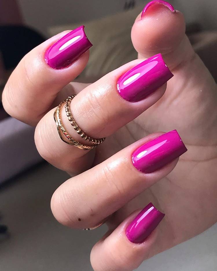 Pessoa de pele clara com unha média quadrada viva magenta.