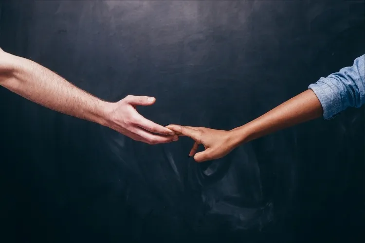 Foto de mãos de casal se afastando, simbolizando término de relacionamento