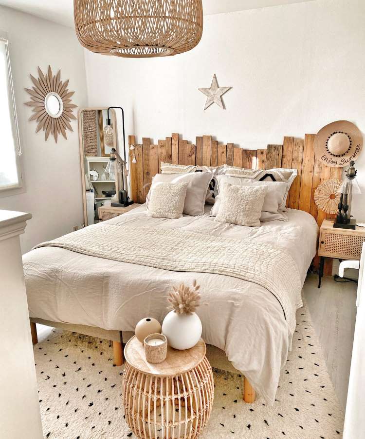 Quarto de casal com espelho retangular no canto da parede e outro com moldura de sol, pendurado na parede. Cores predominantes: off-white, madeira e preto
