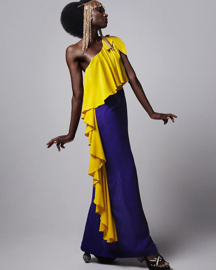 Modelo com vestido longo azul e amarelo.