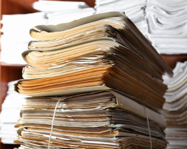 Muitos registros antigos um em cima do outro, ao fundo, mais registros em um móvel