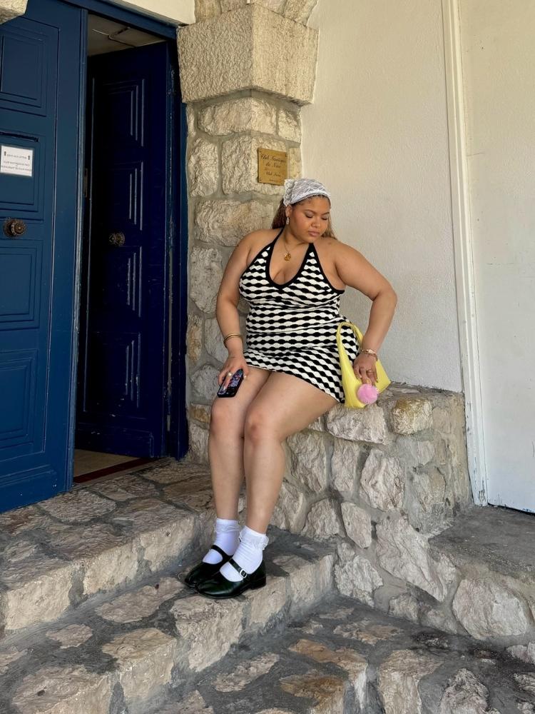 Mulher de pele clara usando vestido curto branco e preto, sapato mary jane e meia 3/4, além de bandana de renda