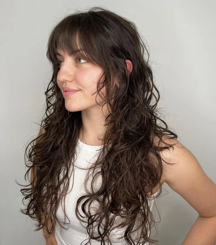 mulher de cabelo longo ondulado castanho e franja média