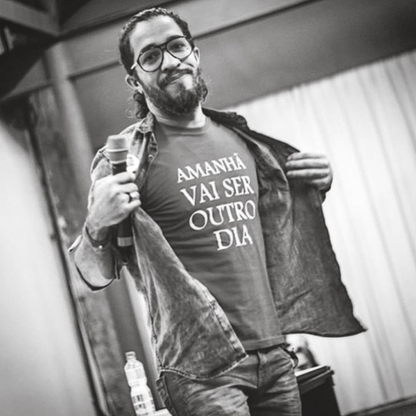 Foto em preto e branco de Jean Wyllys usando camiseta escrito "amanhã vai ser outro dia" e jaqueta 