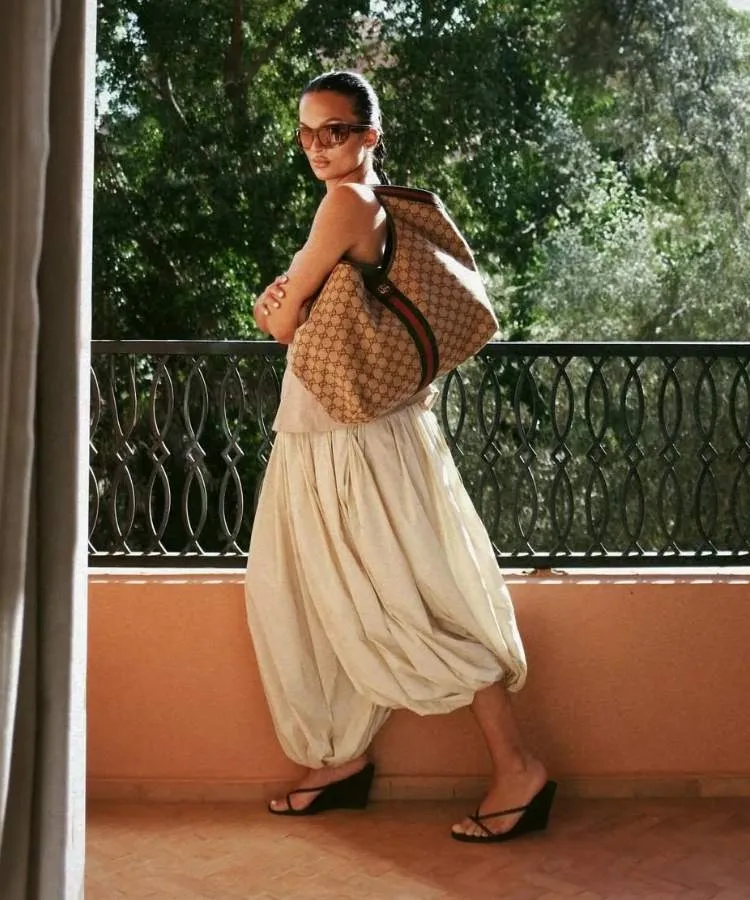 Foto de mulher usando calça aladim off white com tamanco de tiras e salto anabela preto