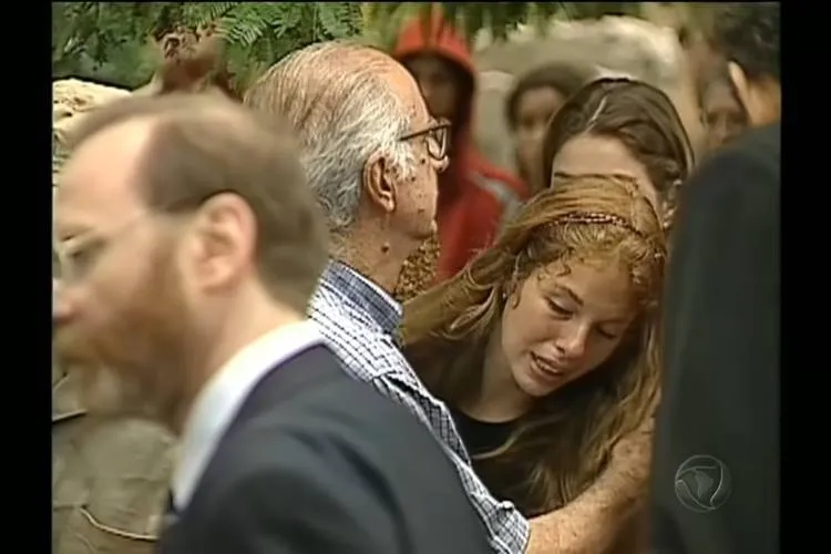 Suzane abraçada com um senhor de cabelos brancos durante o velório de seus pais.