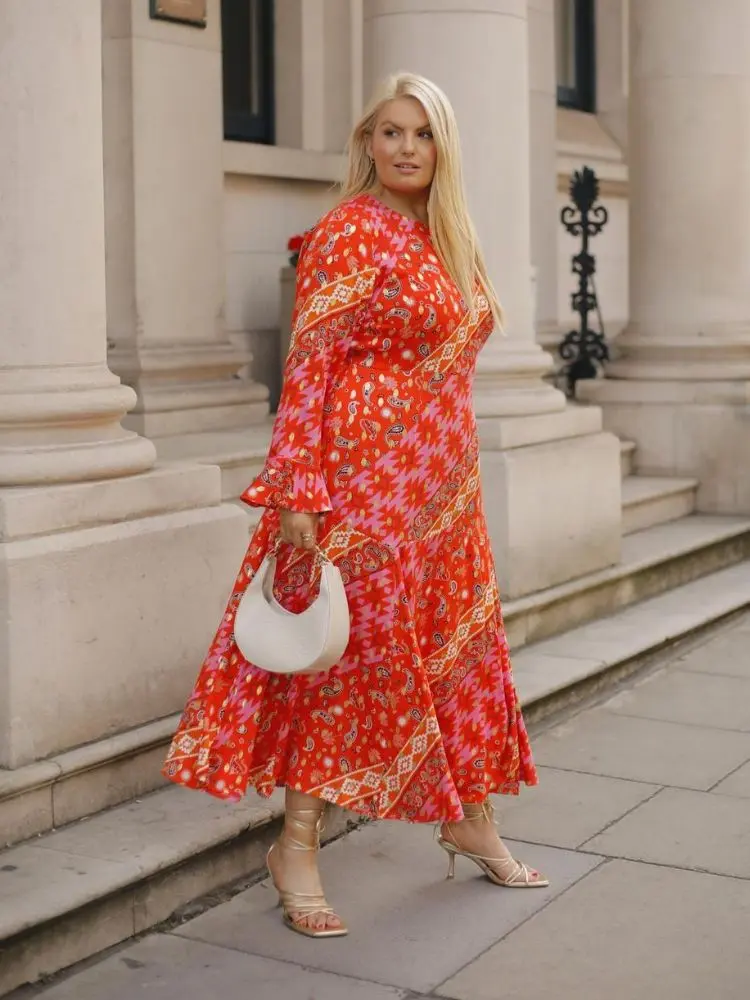 mulher usando vestido vermelho estampado com sapato de salto dourado