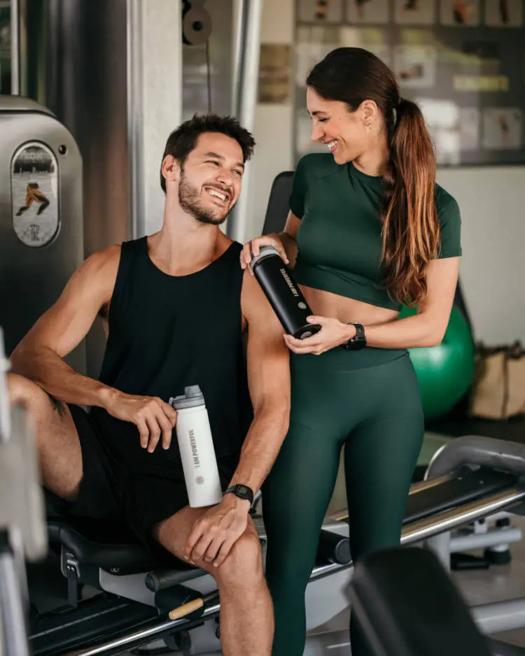 Casal na academia com uma garrafa térmica.