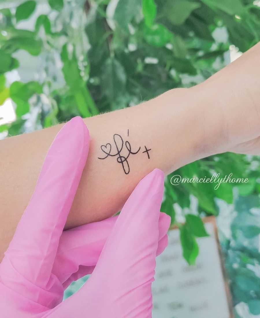 Foto de tattoo com a palavra fé.