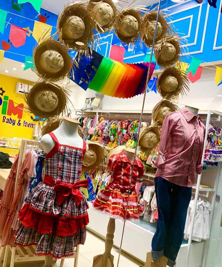 Vitrine com chapéus de palha, manequins com roupas típicas da festa, bandeirinhas e decoração