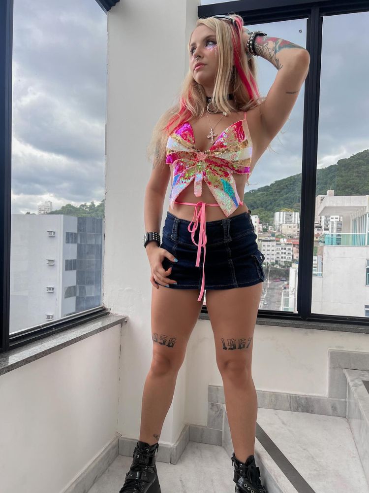Mulher de pele clara usando top de borboleta e minissaia preta 