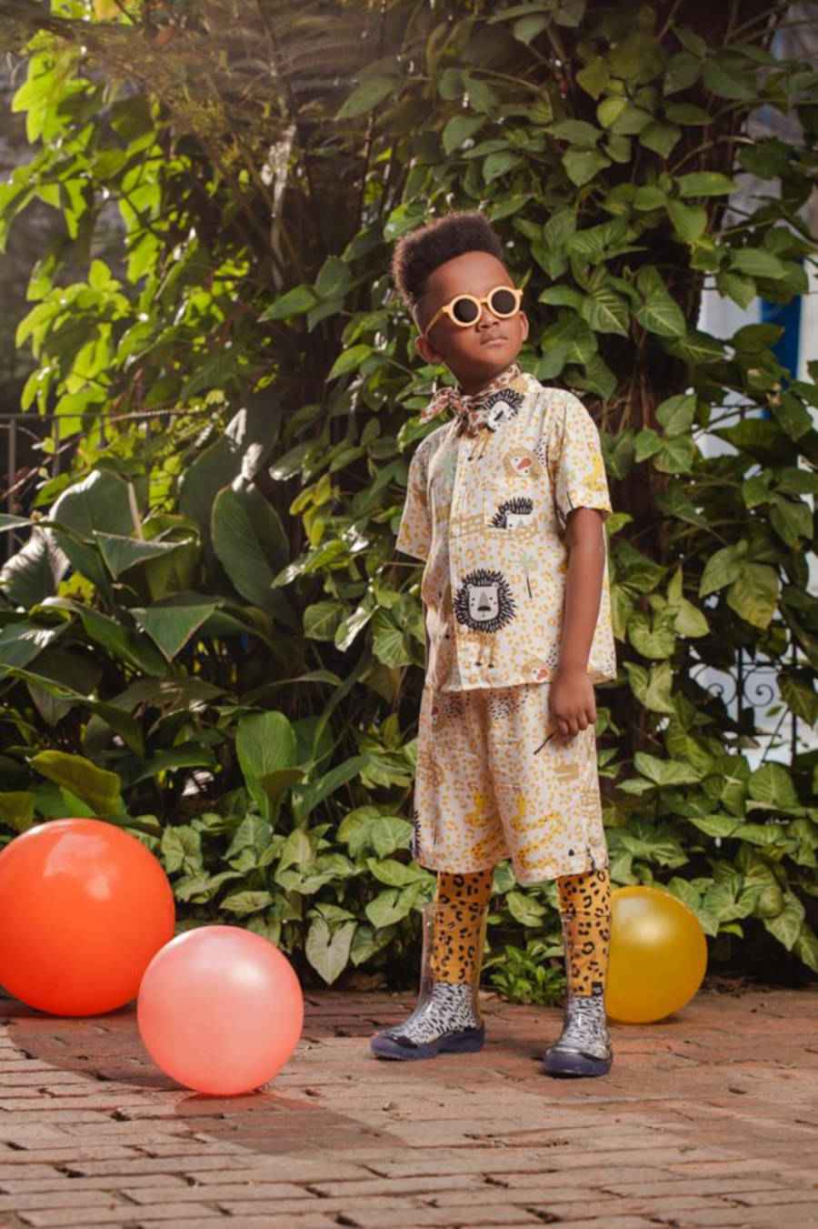 Imagem de menino com óculos escuro com bordas amarelas e roupa com estampa de animal print