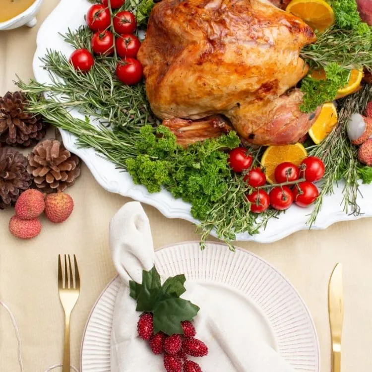 Uma mesa de uma ceia de natal com um peru com decorações de frutas