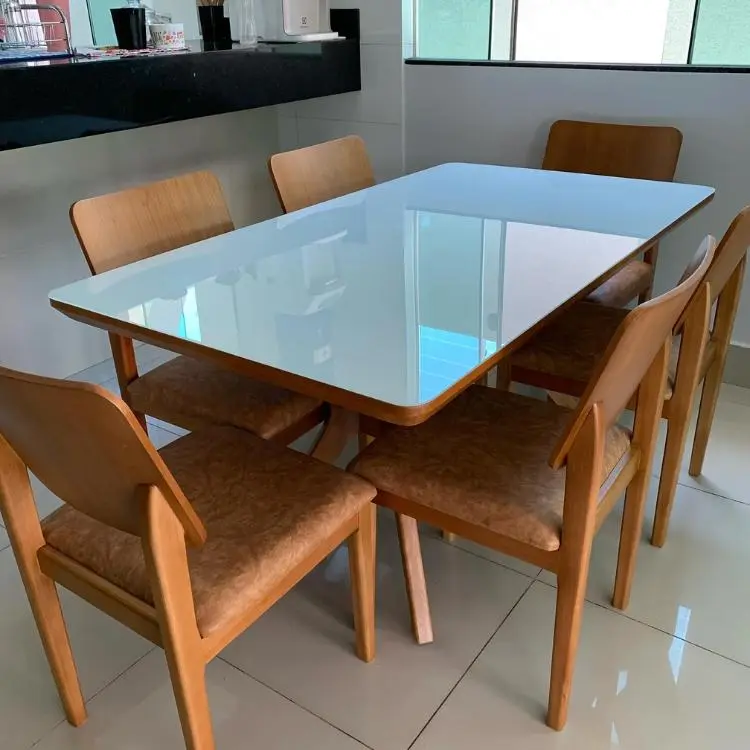 Mesa de jantar em madeira com tampo de vidro e cadeiras em madeira com estofado em couro bege