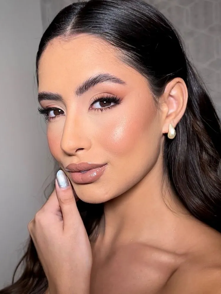 Mulher de pele clara de maquiagem em tons marrons, blush suave e iluminador
