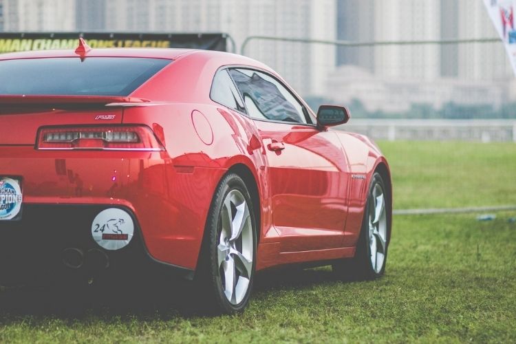 Imagem de um carro vermelho de costas em cima de um gramado. dica de compra carro seminovo