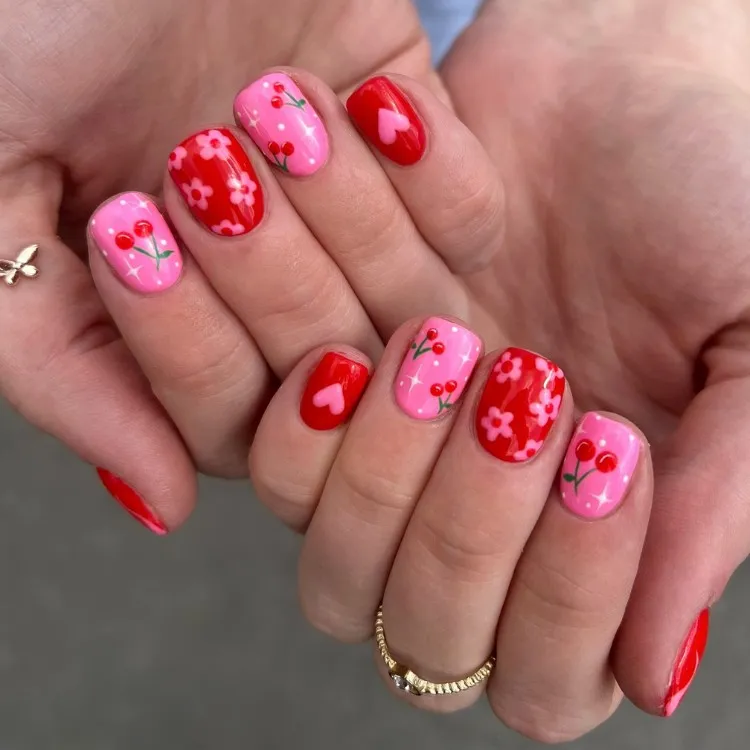 Unhas curtas com desenhos de cereja, flores e coração em rosa e vermelho