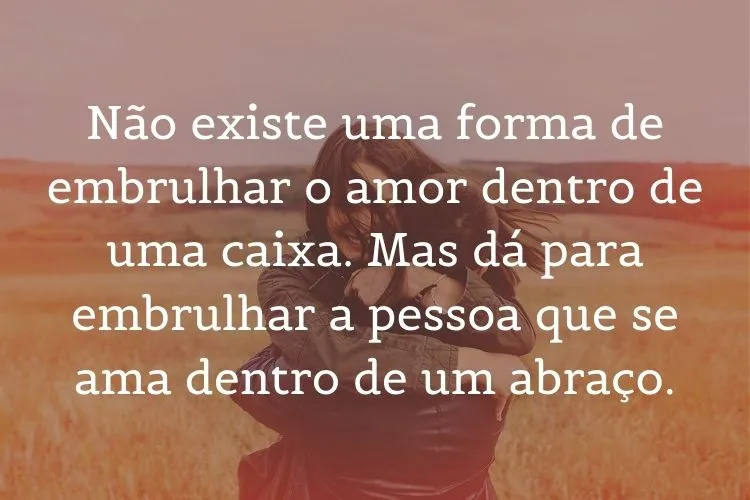 Foto de duas pessoas se abraçando no campo e frase: Não existe uma forma de embrulhar o amor dentro de uma caixa. Mas dá para embrulhar a pessoa que se ama dentro de um abraço.  