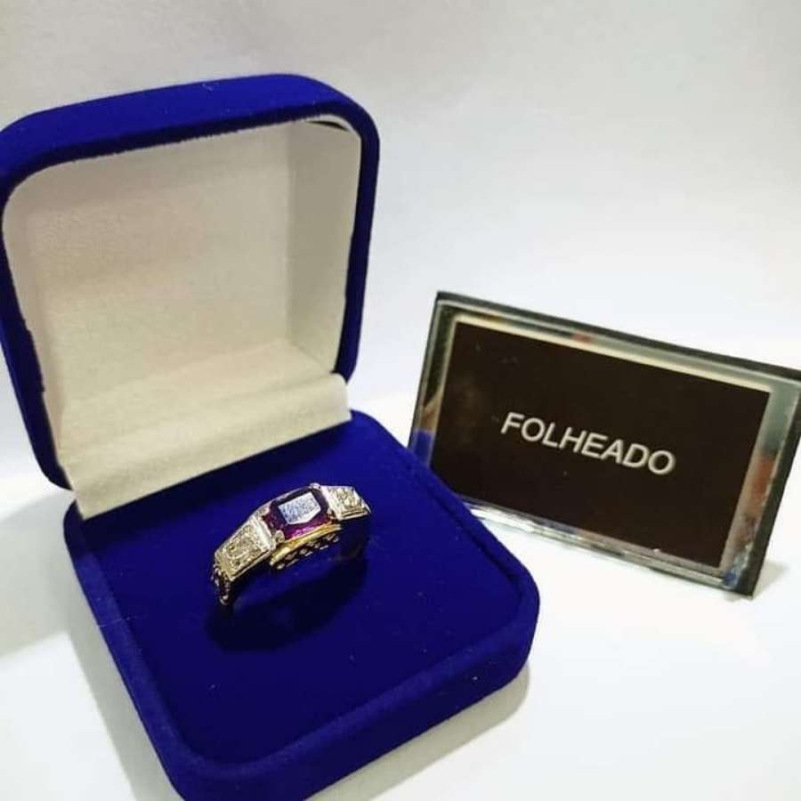 Anel dourado e prateado com pedra roxa em caixa azul