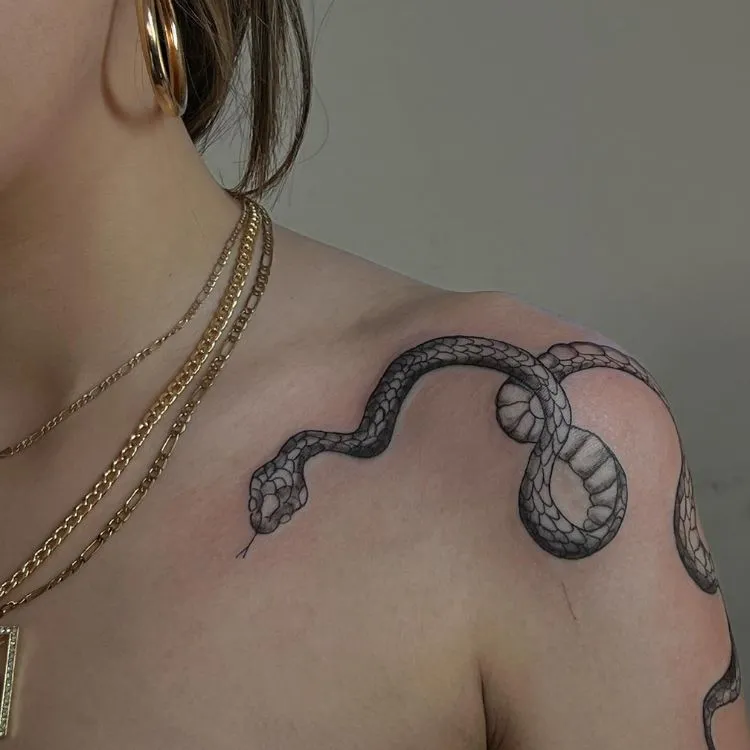 uma mulher com uma cobra tatuada no ombro