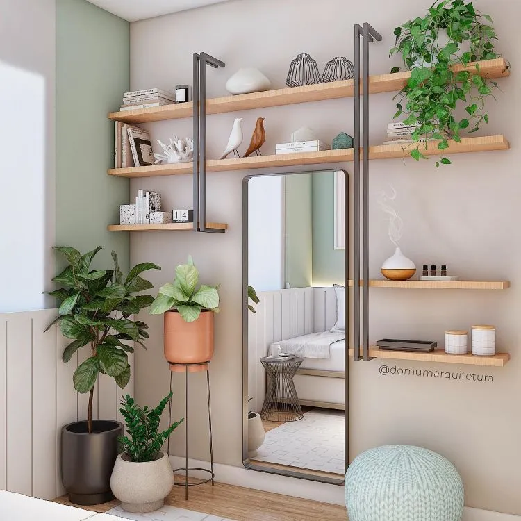 Quarto com espelho, estante aberta com itens decorativos, vasos com plantas no chão e um vaso pendente com jiboia ao alto da prateleira.