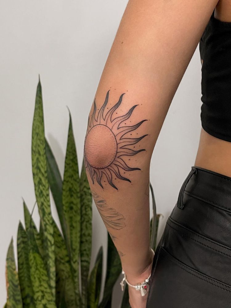 Cotovelo tatuado com raios solares