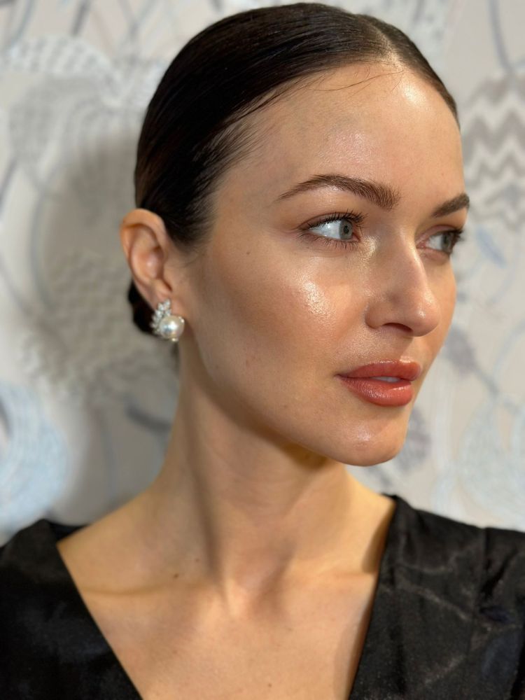 Mulher de pele clara e maquiagem natural com brinco e cabelo preso em coque