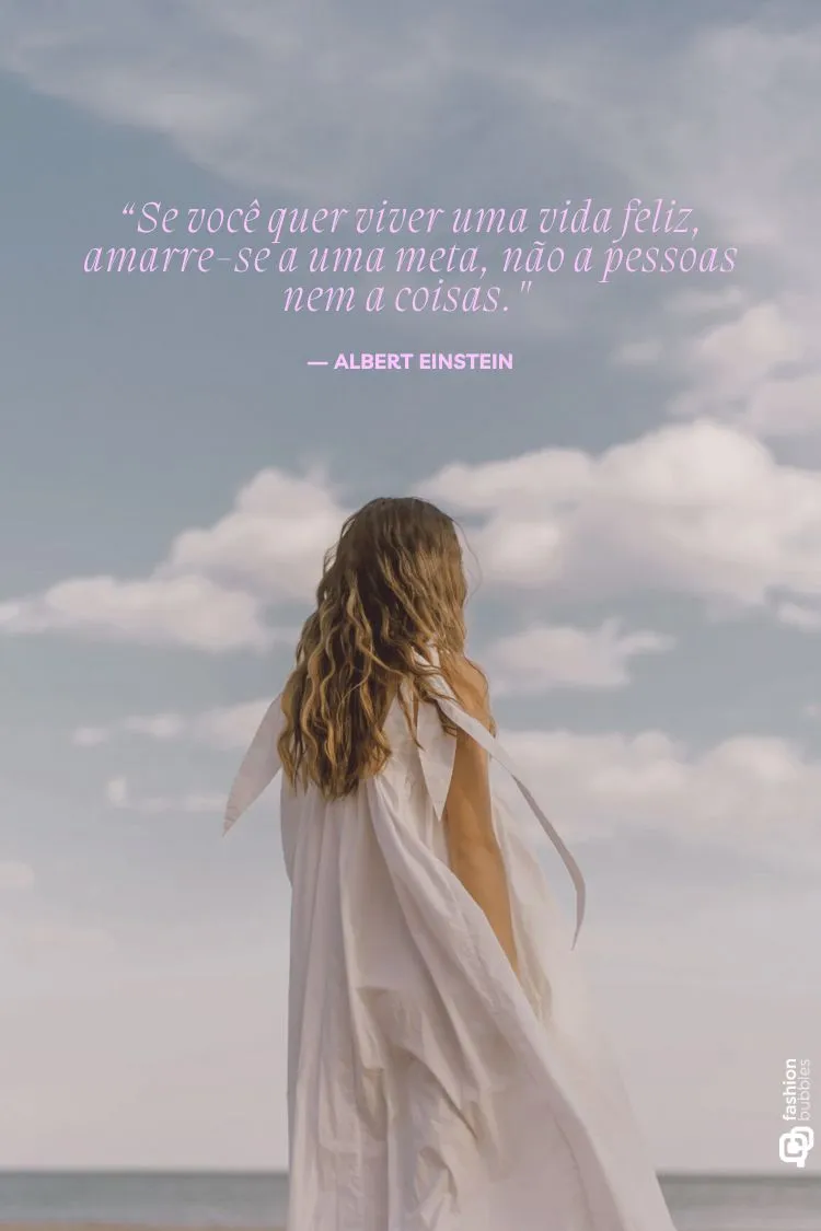 A imagem mostra uma mulher de cabelos longos e ondulados, usando um vestido branco esvoaçante, de costas para a câmera, olhando para o horizonte sob um céu claro com nuvens esparsas. A frase (citações sábias) "Se você quer viver uma vida feliz, amarre-se a uma meta, não a pessoas nem a coisas. - ALBERT EINSTEIN" está sobreposta.

