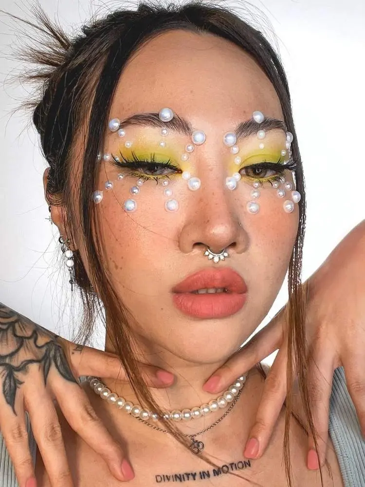 Mulher de origem asiática com sombra amarela e pérolas ao redor dos olhos 