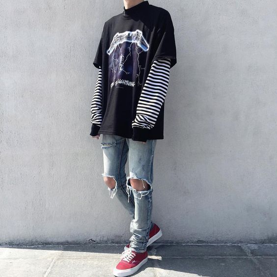 E-boy com calças rasgadas, camisas sobrepostas e tênis colorido Estilo de um e-boy