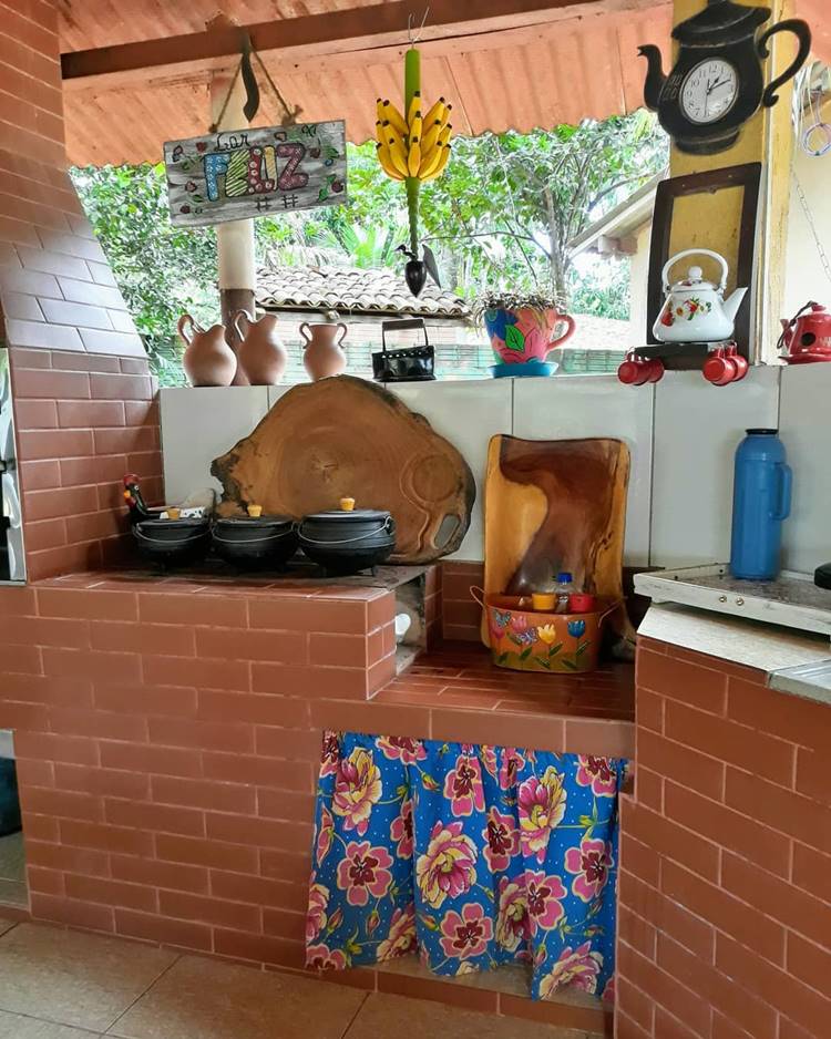Fogão à lenha com panelas de ferro, tábua de churrasco, garrafa de café azul e outras decorações