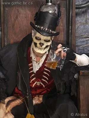 Homem com maquiagem de caveira, cartola, casaco preto, blusa vermelha 