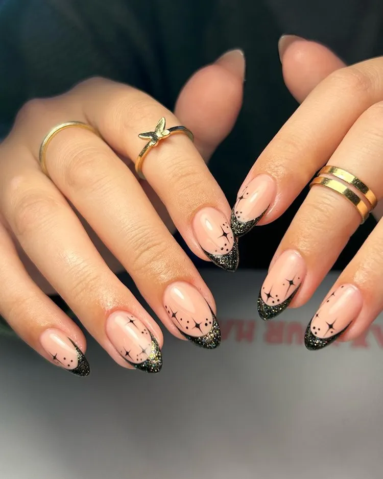 Mão com unhas decoradas para Natal ou Ano Novo na cor preto, com estrelas e glitter