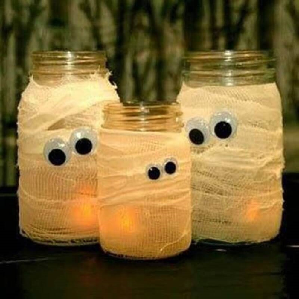 Pote de vidro envolvido com gazes e olhos. Decoração de Halloween com pote de vidro, gazes, olhos e luzes.