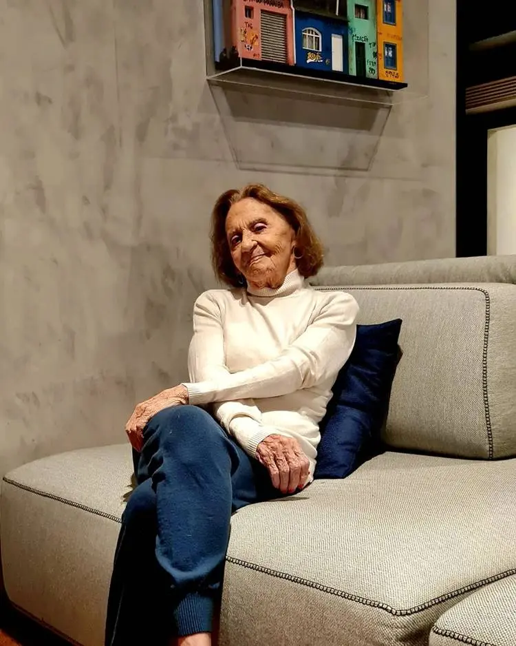 Laura Cardoso hoje em dia sentada em sofá luxuoso.
