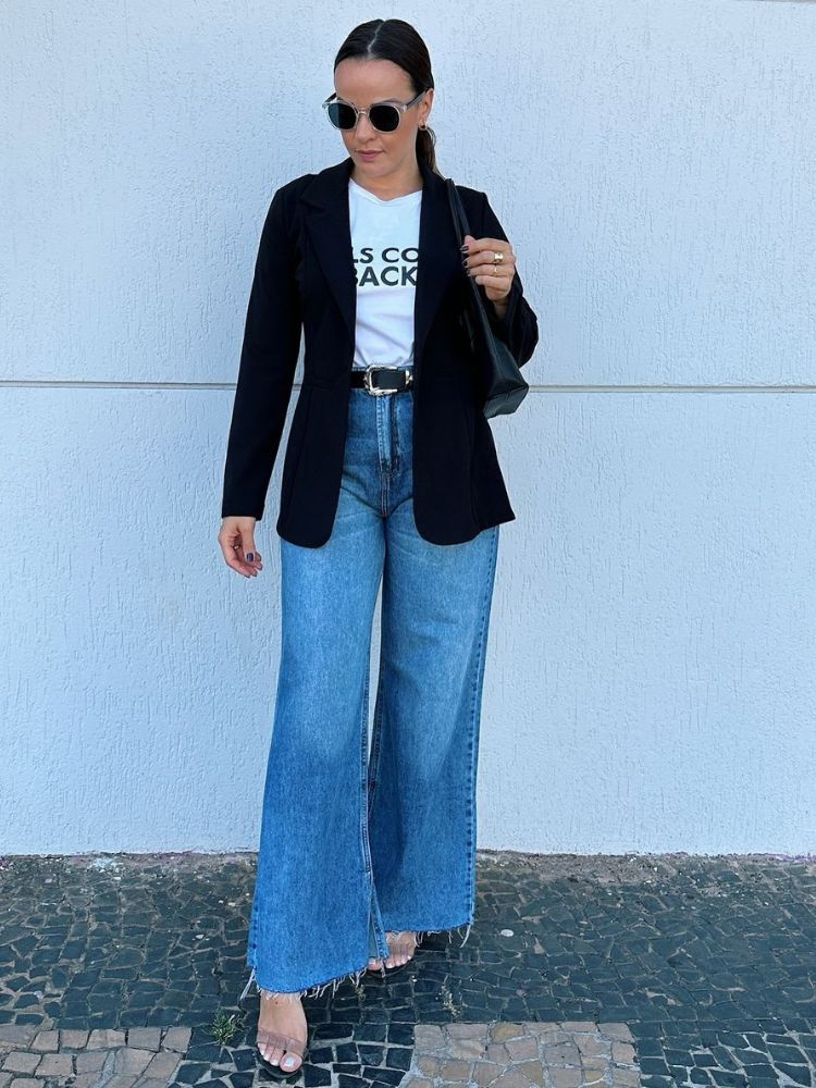 Mulher de pele cara com blusa branca, blazer preto e calça jeans wide leg
