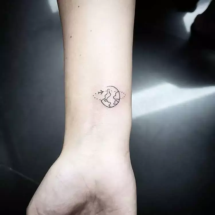 tatuagem no pulso de mundo com avião ao redor