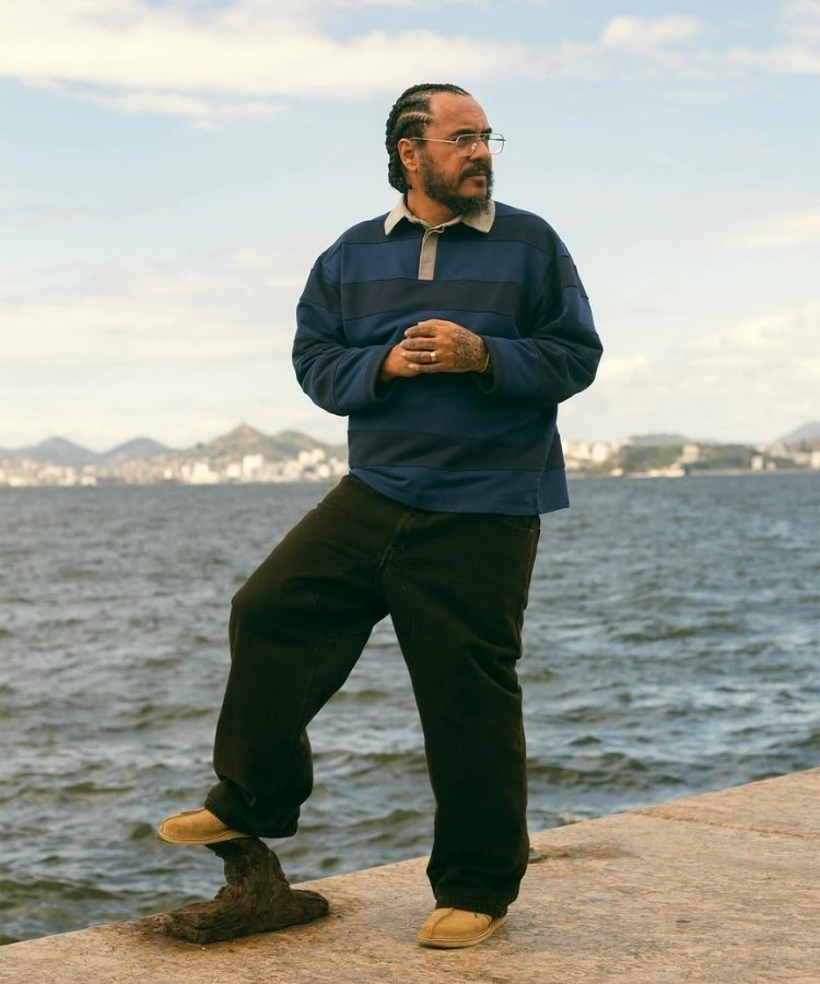 Modelo usando camisa polo listrada de manga comprida com modelagem oversized e calça preta