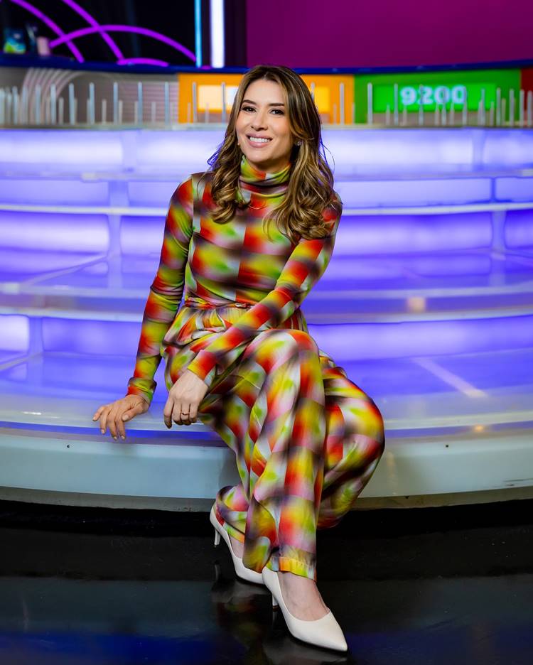 Rebeca Abravanel com look colorido e scarpin off whit sentada na roleta do Roda-roda Jequiti