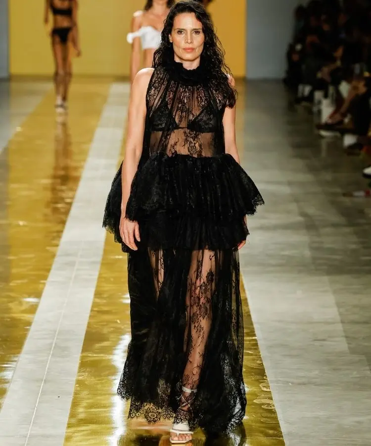 Foto de modelo na passarela usando vestido de renda preto